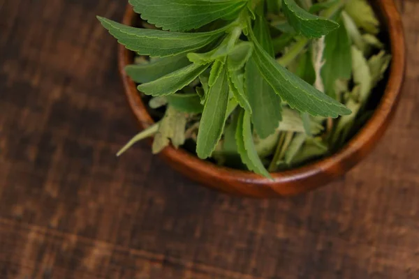 Stevia rebaudiana.Torr och färsk stevia i en träkopp på ett träbord — Stockfoto