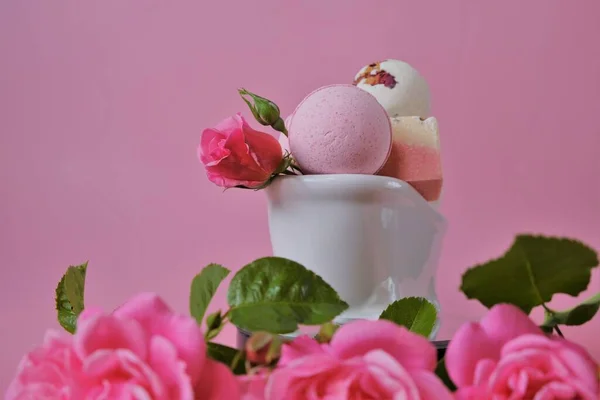 Bombas de banho com extrato de rosa em um banho de cerâmica e rosas cor-de-rosa. Flower Bath Bombs.Beleza e aromaterapia. Cosméticos veganos orgânicos. — Fotografia de Stock