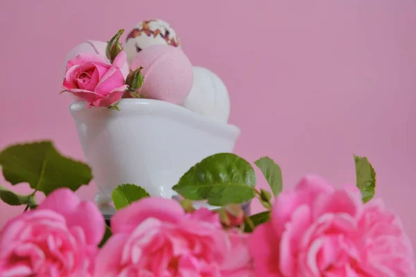 Bombas de banho com extrato de rosa em um banho e rosas rosa em um fundo rosa.Bombas de banho rosa e flores rosa rosa. Flower Bath Bombs.Beleza e aromaterapia. Cosméticos veganos orgânicos. — Fotografia de Stock