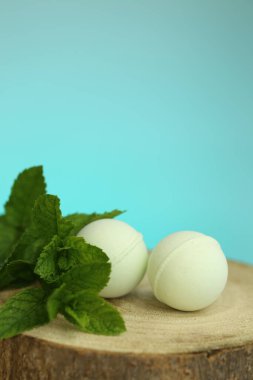 Nane Banyosu bombaları. Nane özlü banyo bombaları. Yeşil banyo bombaları ve mavi bir arka planda kesilmiş bir testerenin üzerindeki nane parçaları.