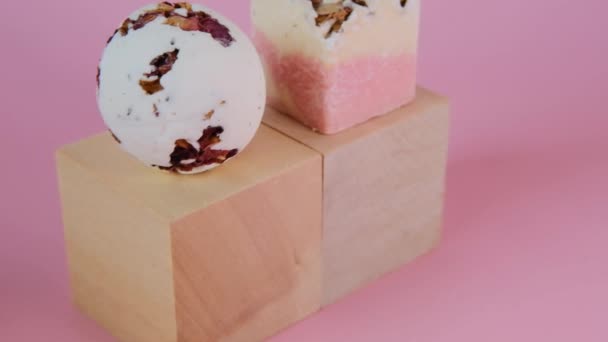 Bombas de banho.Trufas de banho cosméticas .Flower Bath Bombs com extrato de rosa em blocos de madeira em um fundo rosa claro — Vídeo de Stock