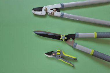 Bahçe aletleri. Makaslar, yeşil arka planda kesiciler. Bahçe bitkileri budanma aletleri. Bahçe ve tarım aletleri.