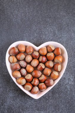 Fındık hasadı. Siyah arka planda bir kalp plakasında fındık.. 