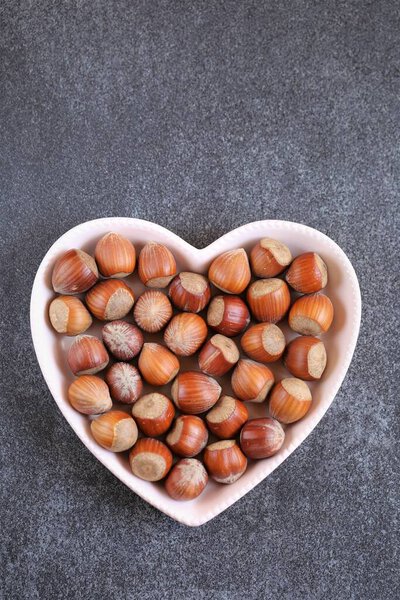 Урожай орехов. Орешек в сердечной пластине на черном фоне.. 