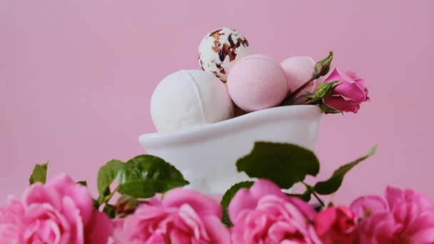 Badebomben in einem Keramikbad und rosa Rosen. Rotation. Schönheit und Aromatherapie. Blütenbad Bomben mit Rosenextrakt. Vegane Bio-Öko-Kosmetik. — Stockvideo