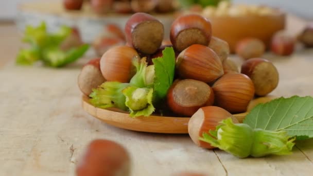 Avelãs com folhas verdes em uma mesa de madeira.Colheita de avelã. Gorduras saudáveis. lanche saudável. — Vídeo de Stock