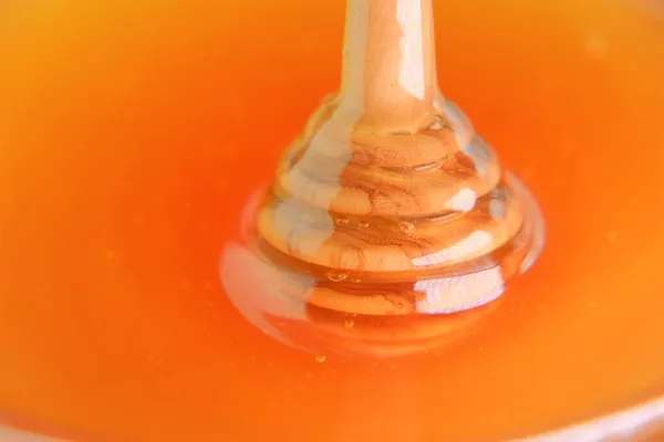 Pałeczka miodu. Ciekły miód w przezroczystym szklanym słoiku z dipper.stick do miodu w filiżance .Zdrowa naturalna słodycz. Miód organiczny. — Zdjęcie stockowe