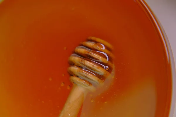 Honey stick . Liquid honey in a transparent glass jar with dipper.stick for honey in a cup .Healthy natural sweetness. Organic honey. — Stock Photo, Image