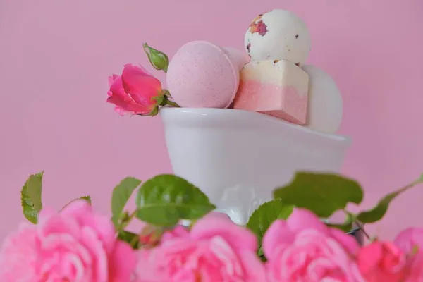 Bombas de banho com extrato de rosa em um banho decorativo de cerâmica e rosas rosa em um fundo rosa. Flower Bath Bombs.Cosméticos veganos orgânicos. Beleza e aromaterapia. — Fotografia de Stock