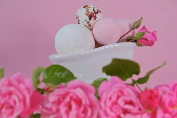 Bombas de banho com extrato de rosa em um banho e rosas rosa em um fundo rosa. Flower Bath Bombs.Cosméticos veganos orgânicos. Beleza e aromaterapia. — Fotografia de Stock