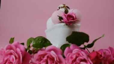 Seramik banyoda banyo bombaları ve pembe güller. Rotasyon. Güzellik ve aromaterapi.