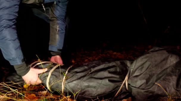 Asesino y cadáver. Escena del crimen. Concepto de asesinato y crimen. Maniaco y víctima en una bolsa negra en un parque oscuro.Maniaco arrastra a su víctima muerta en el parque abandonado nocturno. El maníaco arrastra a la víctima — Vídeo de stock