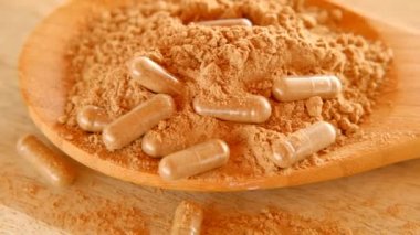 Guarana tozlu kapsüller. Guarana kapsülleri ahşap bir masada tahta bir kaşıkta guarana tozunda. Doğal tonik, ampuller ve vitaminler. Sağlıklı beslenme. Spor beslenmesi