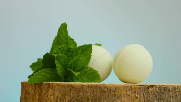 Green bath bombs and sprigs of peppermint on a blue background.Bath bombs with mint extract. Rotation. Beauty and aromatherapy. Organic vegan eco cosmetics — Stock Video