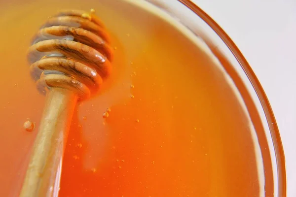 Miel en un vaso de vidrio.Dulzura natural saludable. Palillo de miel fresca orgánica. Miel líquida en un frasco con cazo. —  Fotos de Stock