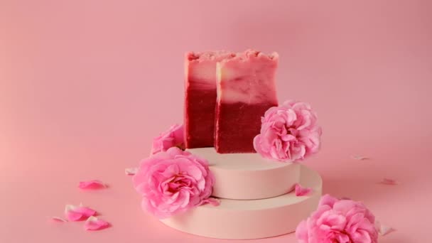 Mýdlo Rose. Růžové mýdlo tyčinky a růžové růže na pódiu na růžovém pozadí. — Stock video