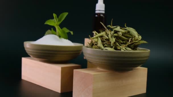 Stevia rebaudiana. Kurumuş stevia, stevia tozu yaprakları ve stevia sıvısı koyu yeşil arka planda ahşap podyumlarda bulunuyor. Organik doğal tatlandırıcı.. — Stok video