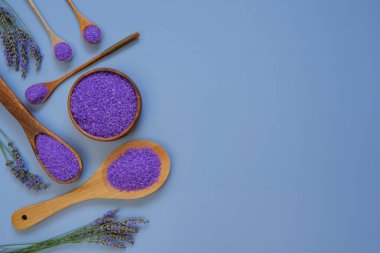 Mor lavanta tuzu ve lavanta özlü kaşık seti ve lavanta çiçekleri mavi arka planda. Lavanta özlü organik kozmetik.
