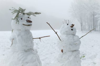 Karlı bir arazide kardan adam çifti. Şimdi de kardan adam figürü. Kar heykeli. Kardan adam yapmak için. Kış eğlencesi ve oyunlar. Noel ve Yeni Yıl Festivali. 