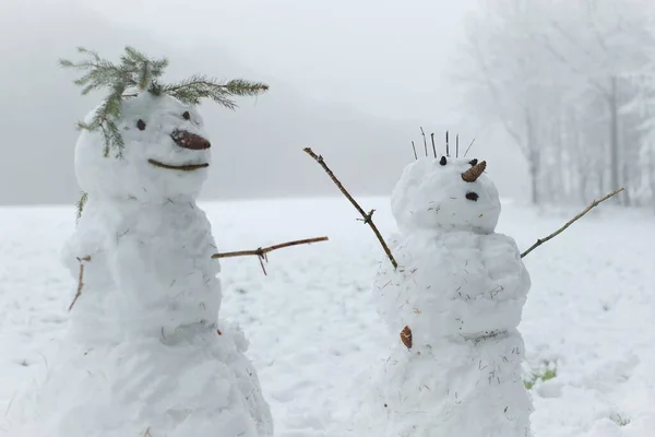 雪人夫妇在雪地里。雪人形象。做雪人，做雪人。冬天的乐趣和游戏。圣诞及新年佳节. — 图库照片
