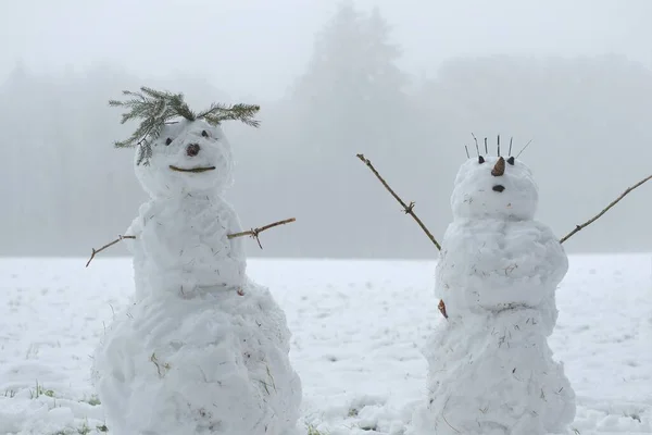雪人夫妇在雪地里。雪人形象。做雪人，做雪人。冬天的乐趣和游戏。圣诞和新年佳节。冬季 — 图库照片