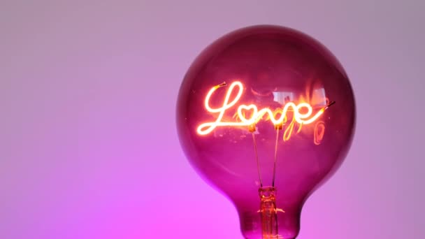 Valentines Day. Love light bulb.Turning on a light bulb.purple Light bulb with the inscription love on a purple background. Love and relationship symbol.Love concept. — Stock Video