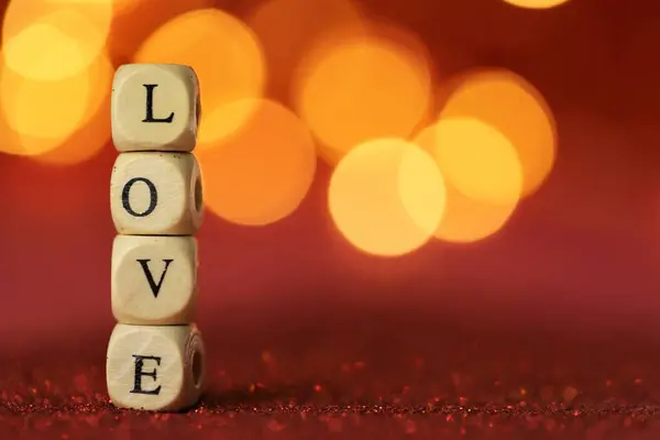 Symbol miłości. Walentynki. Napis miłość z liter na czerwonym tle brokatu ze złotym bokeh.Uroczyste romantyczne tło . — Zdjęcie stockowe