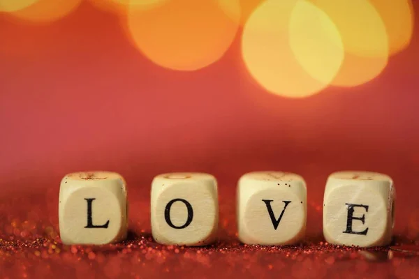 Symbol miłości. Walentynki. Napis miłość z liter na czerwonym tle brokatu ze złotym bokeh.Uroczyste romantyczne tło. Miłość i związek — Zdjęcie stockowe