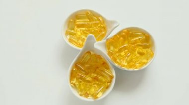 Beyaz arka planda seramik bardaklardaki balık yağı kapsülleri. Dönüşüm. Omega yağ asitleri. Doğal takviyeler ve vitamin.