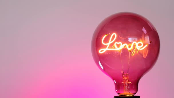 Love concept. Light bulb with the inscription love on a purple background. Love and relationship symbol — Stock Video