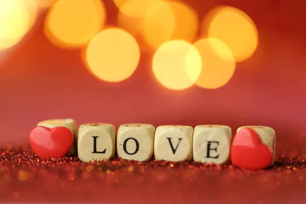 Valentijnsdag. Prachtige feestelijke glanzende achtergrond. Inscriptie liefde gemaakt van houten letters op rode glitter achtergrond met gouden bokeh.Love symbool — Stockfoto