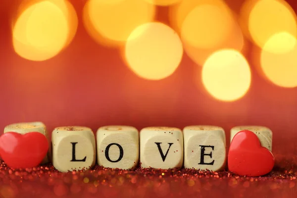 Liefde en relatie.Valentijnsdag. Prachtige feestelijke glanzende achtergrond. Inscriptie liefde gemaakt van letters op rode glitter achtergrond met gouden bokeh.Love symbool — Stockfoto