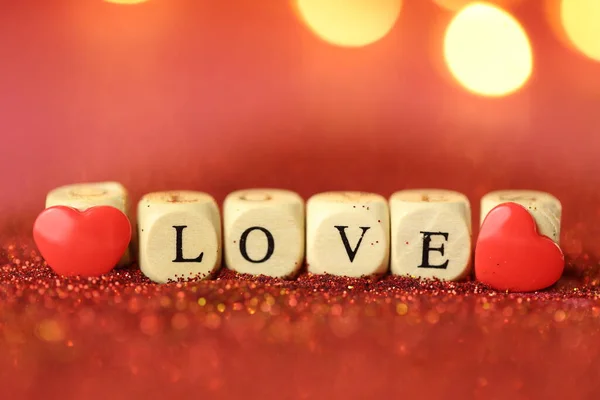 Amor y relación.Día de San Valentín.Hermoso fondo brillante festivo. Inscripción amor hecho de letras de madera sobre fondo de brillo rojo con bokeh.Love oro símbolo — Foto de Stock