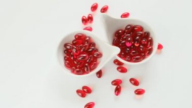Beyaz seramik kaplarda bulunan kril yağı kırmızı jelatin kapsülleri. Beyaz arka planda. Omega yağ asitleri. Doğal takviyeler ve vitamin.