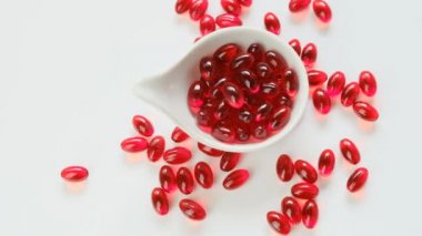 Beyaz arka planda beyaz seramik kaplarda kril yağı kırmızı kapsülleri. Omega yağ asitleri. Doğal takviyeler ve vitamin.