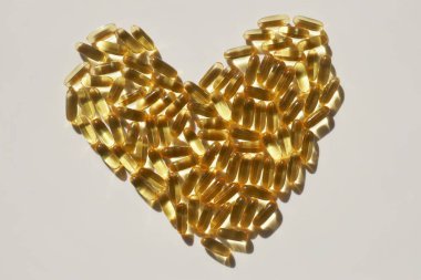 Kalbinde beyaz arka plan şekilli balık yağı kapsülleri. Omega yağ asitleri. Doğal takviyeler. 