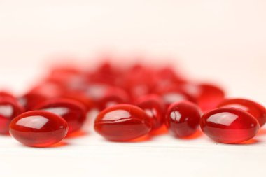 Beyaz ahşap zemin üzerinde kril yağı kırmızı kapsülleri. Doğal takviyeler ve vitamin. Omega yağ asitleri..