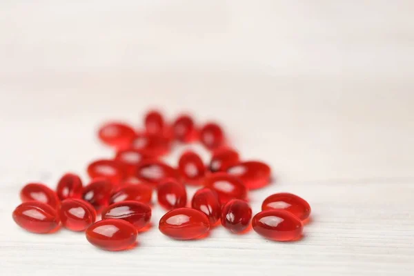 Krill oil red gelatin capsules on a white wooden background .Natural supplements and vitamin