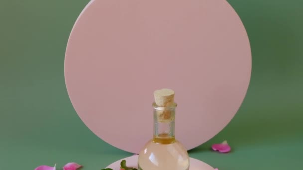 Olej różany w płatkach róż na różowym podium.Aromaterapia i kosmetyki. — Wideo stockowe