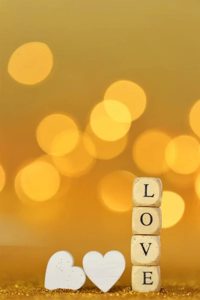Walentynki. Napis miłość wykonana z liter drewnianych i białe serca na tle złoty brokat ze złotym bokeh. Walentynki tło w złote tony.Symbol miłości — Zdjęcie stockowe