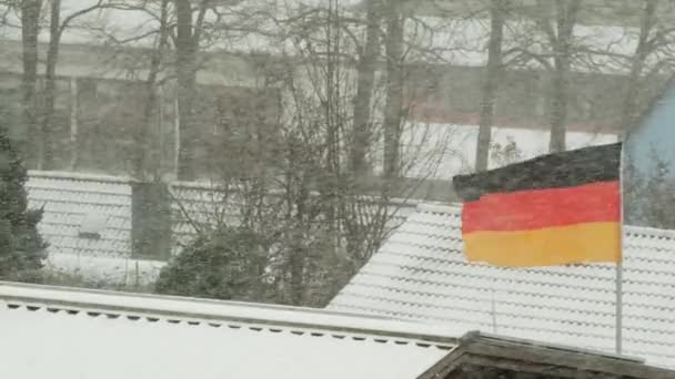 Vlajka Německa a střechy domů za sněhového počasí. Zima v Německu. Zimní sezóna v NDR. Topná sezóna v Německu. — Stock video