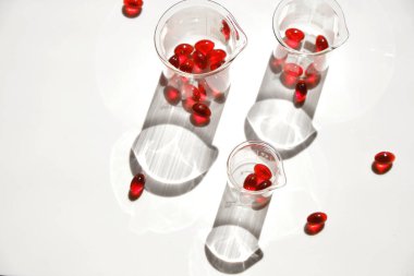 Beyaz bir arka planda laboratuvar kapsüllerinde kril yağı jelatin kapsülleri. Omega yağ asitleri. Uçan kapsüller kırmızı krill yağı. Sağlıklı beslenme ve gıda takviyeleri.