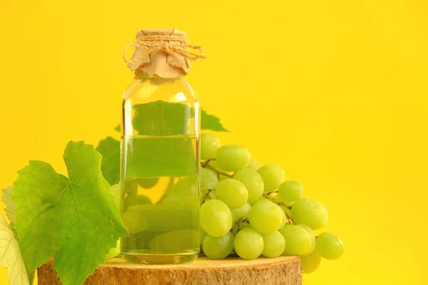 Aceite de semilla de uva. Aceite base para masaje y cuidado de cara y cuerpo. botella y racimo de uvas verdes sobre un fondo amarillo.Organic Natural Bio Grape Seed Oil.natural cosmetics —  Fotos de Stock