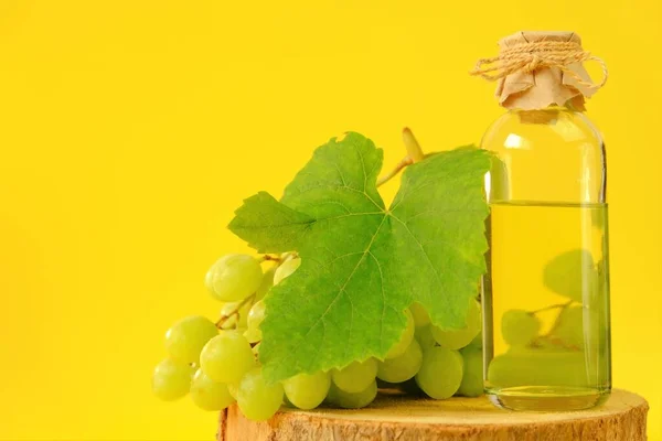 Aceite de semilla de uva. Aceite cosmético base para masaje facial y corporal. botella y racimo de uvas verdes —  Fotos de Stock