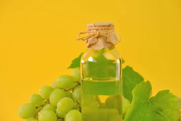 Aceite cosmético de semilla de uva para masaje y cuidado de cara y cuerpo. botella y racimo de uvas verdes sobre un fondo amarillo.Organic Natural Bio Grape Seed Oil.natural cosmetics —  Fotos de Stock