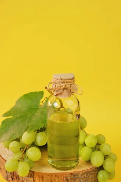 Aceite de semilla de uva. Aceite cosmético base para masaje y cuidado de cara y cuerpo. botella y racimo de uvas sobre un fondo amarillo.Organic Natural Bio Grape Seed Oil.natural cosmetics —  Fotos de Stock