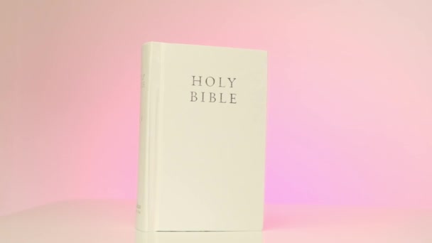 Αγία Γραφή.Χριστιανικό και καθολικό θρησκευτικό σύμβολο. λευκό βιβλίο της Βίβλου σε ροζ φόντο. — Αρχείο Βίντεο