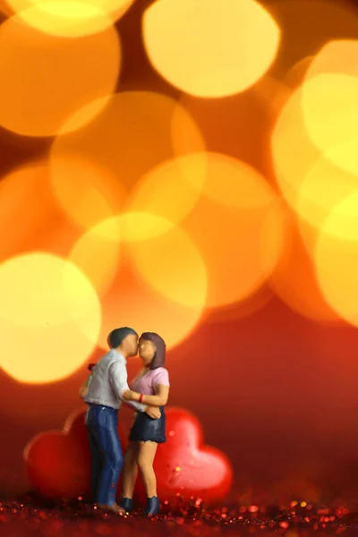 Sevgililer Günü. Aşk sembolü. Aşk biblolarında bir çift, ahşap harflerle yazılan aşk altın bohçalı kırmızı bir arka planda. — Stok fotoğraf