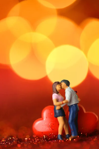 Liefdessymbool. Liefdespaar figuurtjes, Inscriptie liefde gemaakt van houten letters op een rode glitter achtergrond met gouden bokeh.Valentijnsdag achtergrond. — Stockfoto