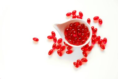 Beyaz arka planda beyaz fincanda kril yağı jelatin kapsülleri. Omega yağ asitleri. Sağlıklı beslenme ve gıda takviyeleri.